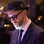 Ein Mann mit Anzug und Sonnenbrille. Er handelt sich dabei um den Keyboarder und Musical Director bei der Eventband Jukebusters für die wir regelmäßig die Tontechniker stellen.