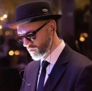 Ein Mann mit Anzug und Sonnenbrille. Er handelt sich dabei um den Keyboarder und Musical Director bei der Eventband Jukebusters für die wir regelmäßig die Tontechniker stellen.
